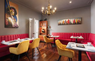 Dining space at Chelsea House in Falmouth. Red booth-style seating, gold chandelier, mustard velvet chairs, wooden flooring 